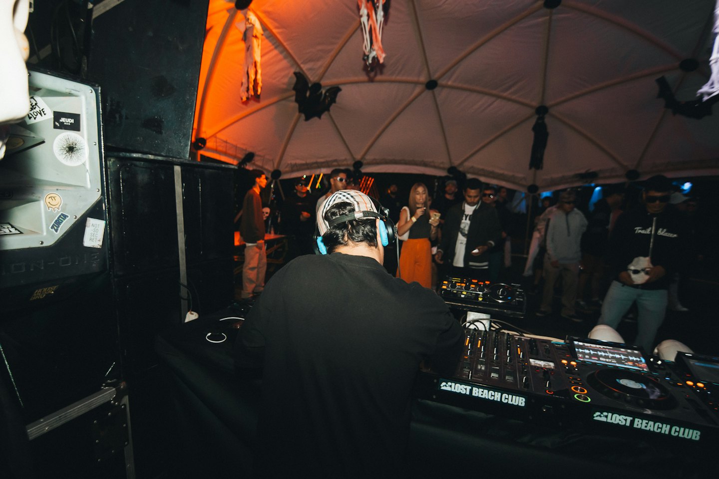 DJ wearing headphones mixes music at a Halloween themed event.